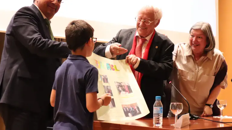 Momento en el que un ni&ntilde;o entrega al padre &Aacute;ngel un trabajo sobre su labor