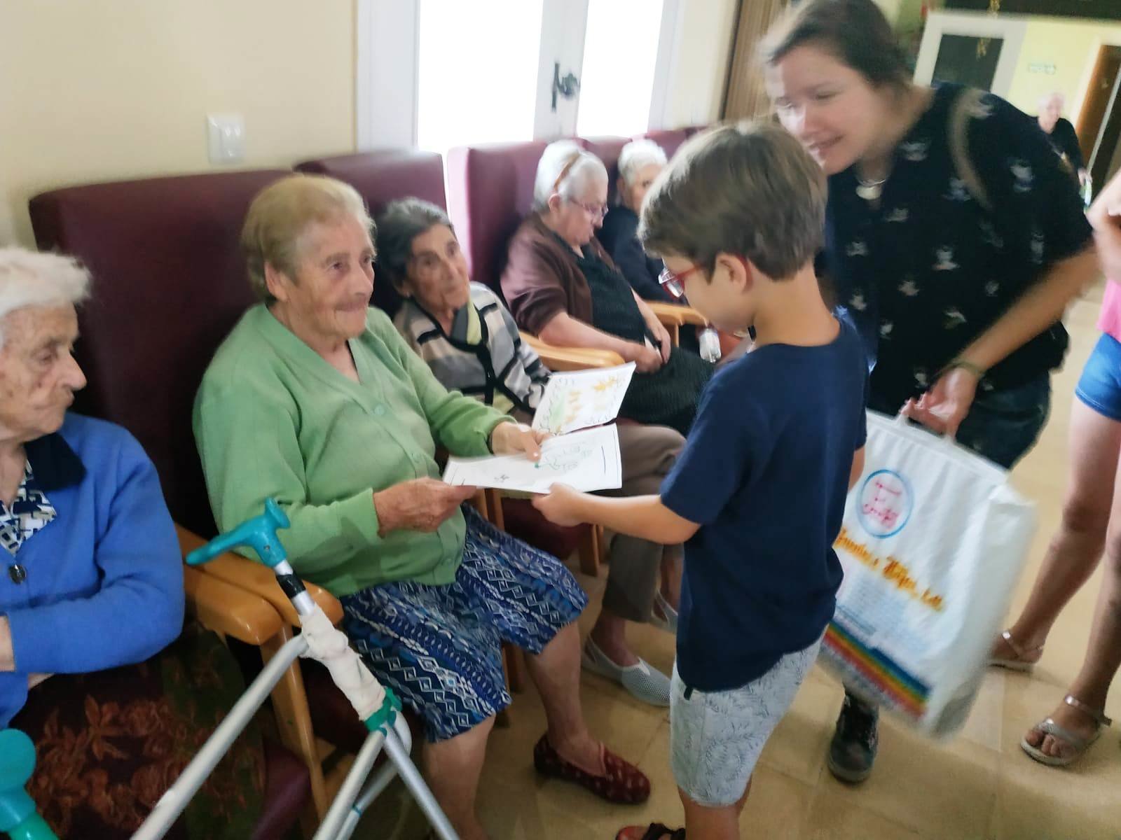 Un niño entrega su dibujo a una residente en Iluminada Martín de Ovelar